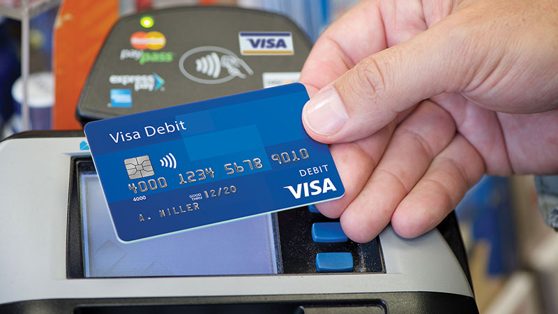Gambar tangan memegang kartu debit Visa.